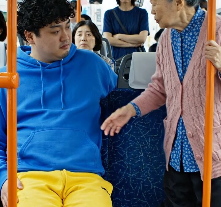 日本語訳  その少年は、隣の空席に座ろうとした老婆を通そうとせず、傲慢な笑みを浮かべて言った。 ――「ここは僕の足が占領しているんだ」と、彼はそう答えると、わざと座席に足を乗せた。  その日、バスは満員だった。乗客たちはカーブで倒れないよう、必死に踏ん張っていた。大声で話す者、スマホを見つめる者、ただ黙って混雑に耐える者など、車内は様々だった。